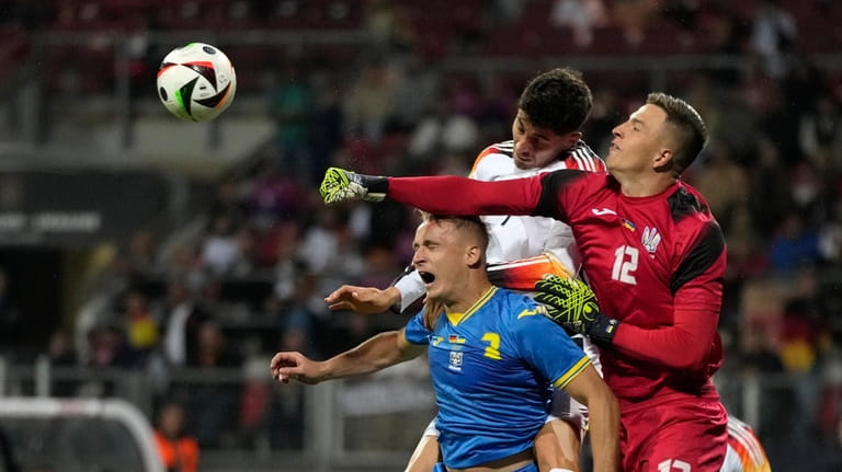 Ukraine's goalkeeper Anatoliy Trubin punches the ball away under pressure...