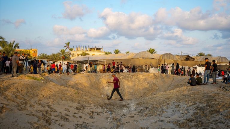 Palestinians look at the destruction after an Israeli airstrike on...