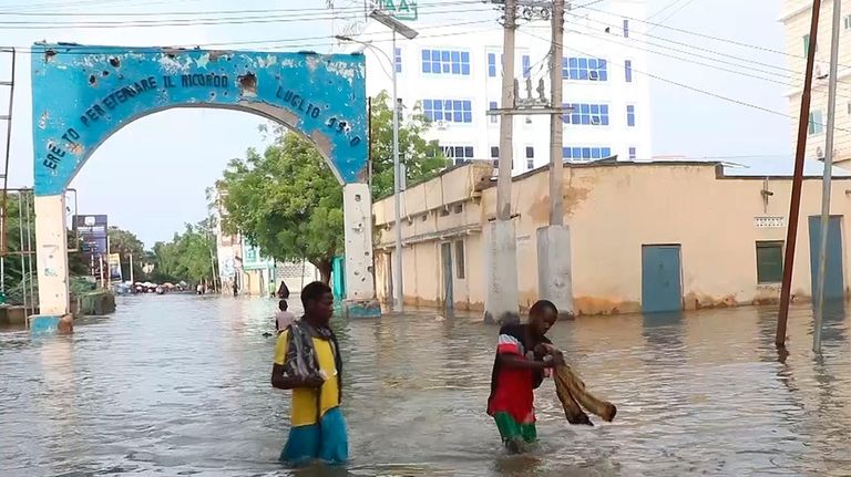 In this image made from video, residents move through floodwaters...