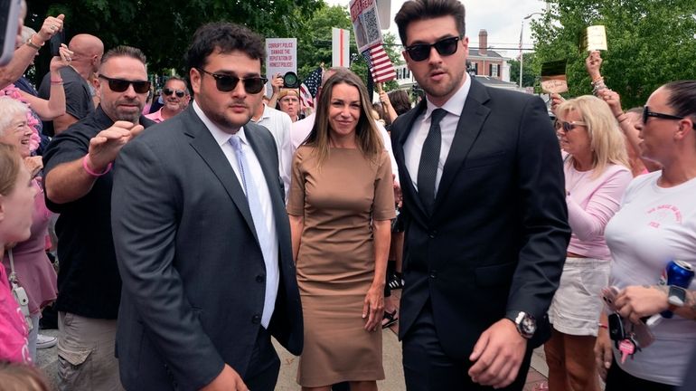 Karen Read, center, is flanked by security as she arrives...