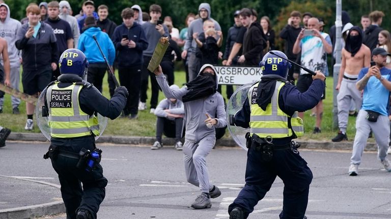 A youth throws a fence post towards police during an...