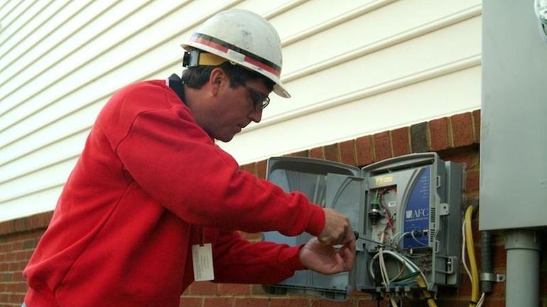 A Verizon technician installs a device, known as an optical...