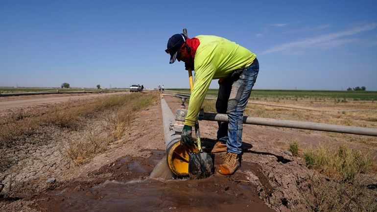 A worker diverts water as a sprinkler system is installed...