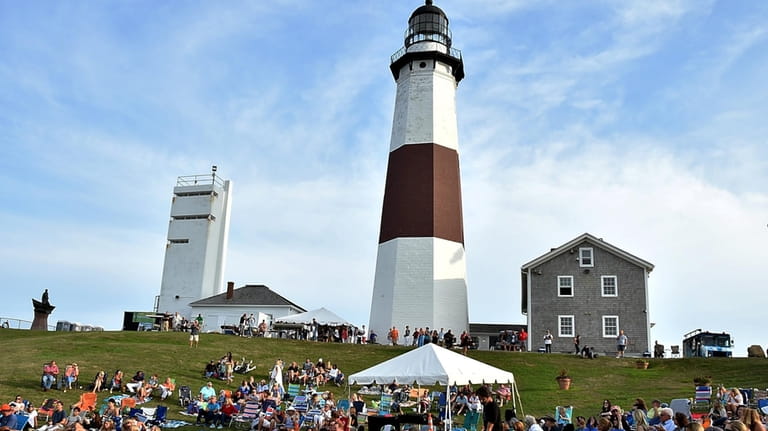 People relax on the slopes of the Montauk Lighthouse.