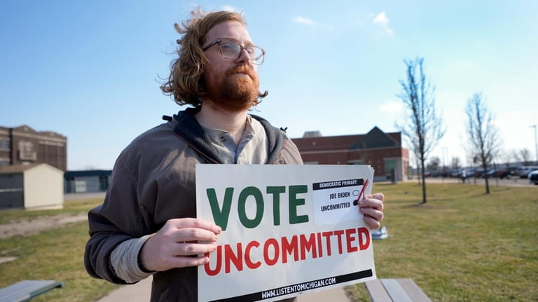 Eric Suter-Bull holds a Vote Uncommitted sign outside a voting...