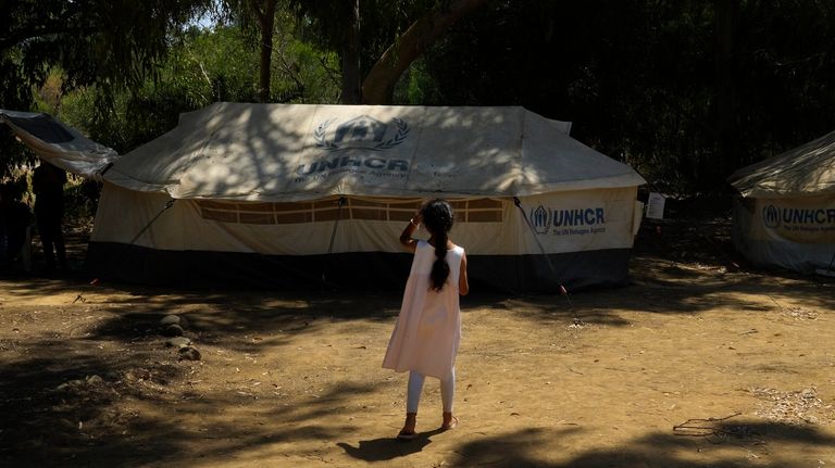 A girl stands in front of a tent at a...