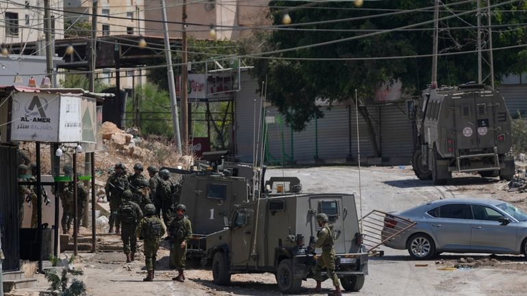 Members of Israeli forces patrol a street during a military...