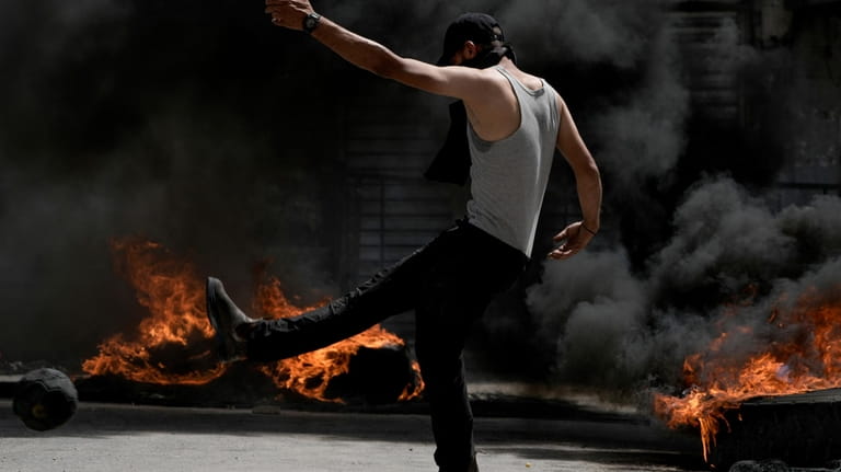 A Palestinian demonstrator burns tires next to a model of...