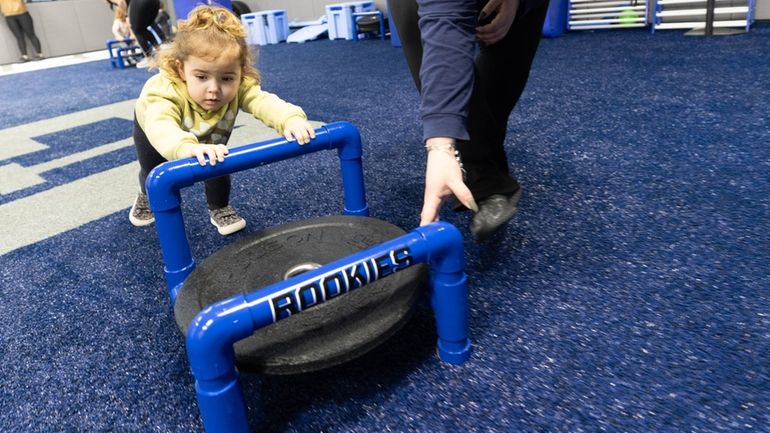 Two-year-old Sadie Loesch pushes a sled with the help of...