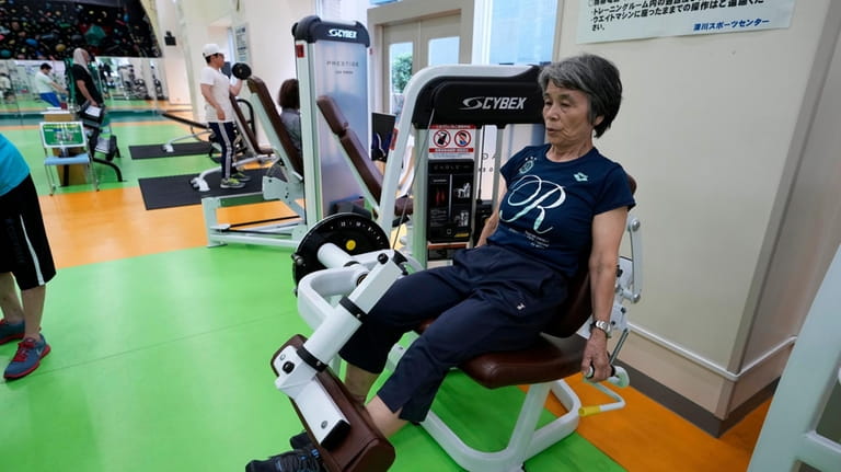 Yasuko Kuroi, 72, uses a leg extension machine as she...
