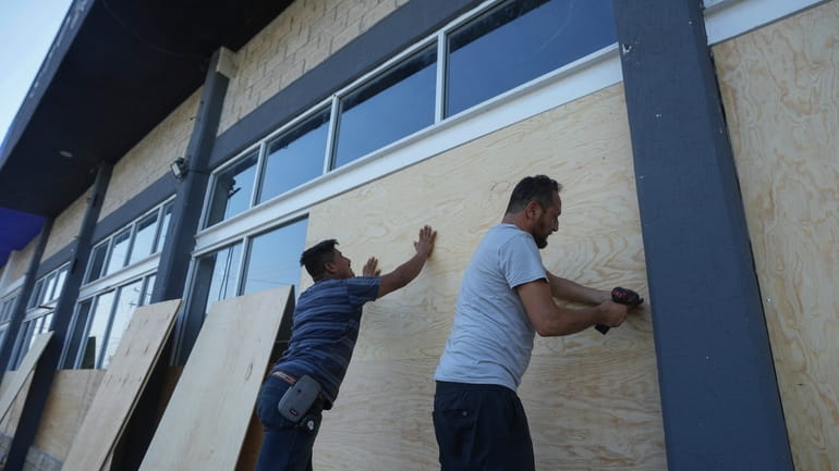 Furniture store employees board up windows for protection ahead of...