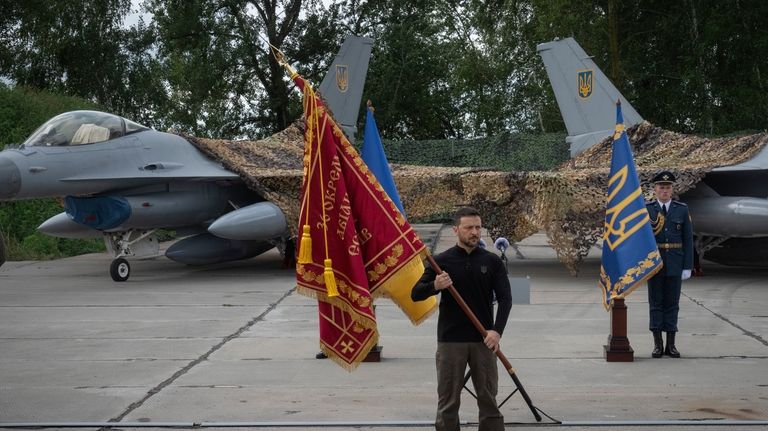 Ukraine's President Volodymyr Zelenskyy hands over the flag of a...