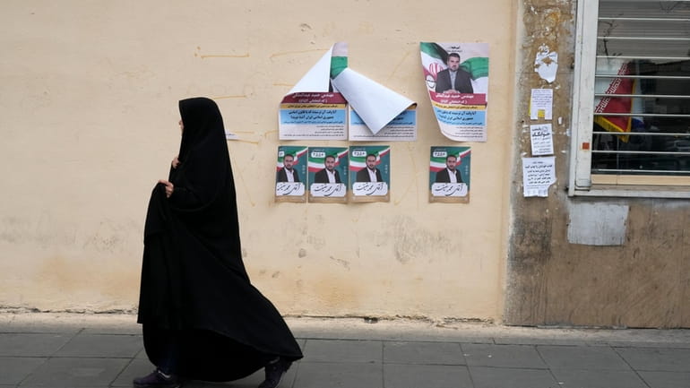 A woman walks past electoral posters of candidates for the...