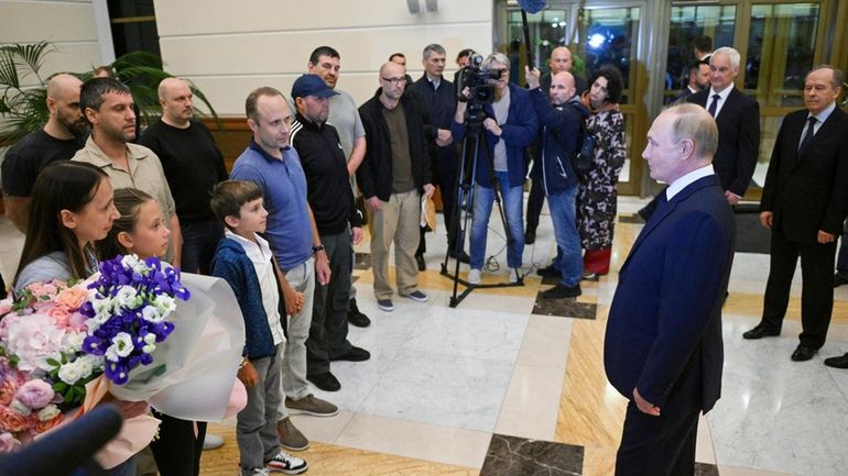 Russian President Vladimir Putin, right, speaks to released Russian prisoners...