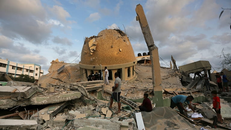 People stand outside a mosque destroyed in an Israeli air...
