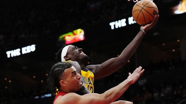 Indiana Pacers forward Pascal Siakam (top) scores past Toronto Raptors...