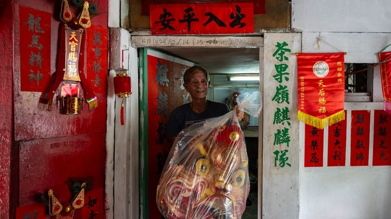 Villager Lo Yuet-ping carries the head prop that's used in...