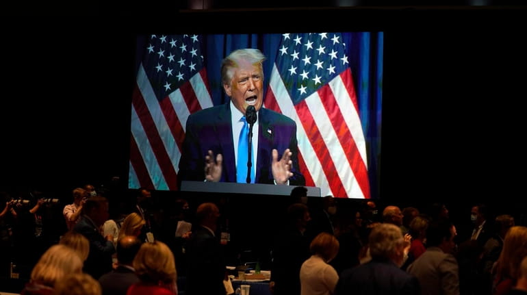A screen displays President Donald Trump as he speaks on...