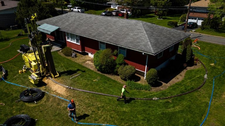 A drill rig for a geothermal heat pump sits outside...