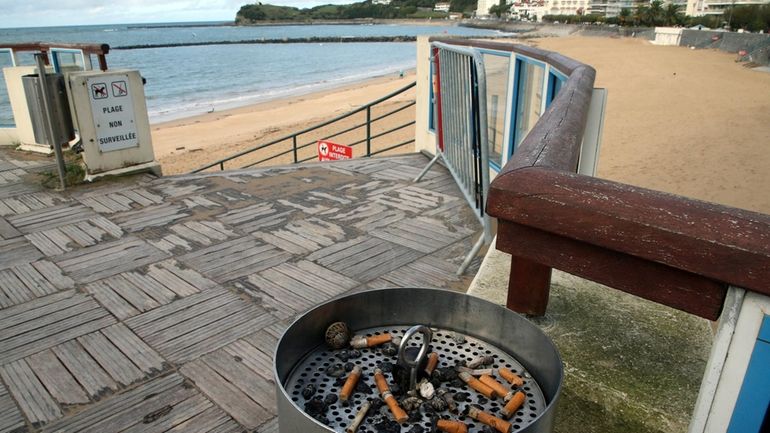 An ashtray with cigarette butts at the edge of the...