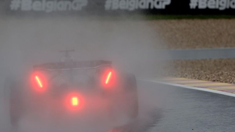 A driver steers his car in the rain during the...