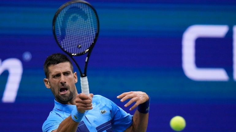 Novak Djokovic, of Serbia, returns a shot to Laslo Djere,...