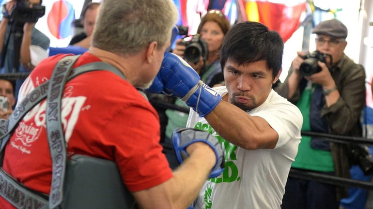Manny Pacquiao and his coach Freddie Roach take part in...
