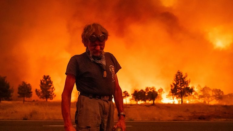 Grant Douglas pauses while evacuating as the Park Fire jumps...