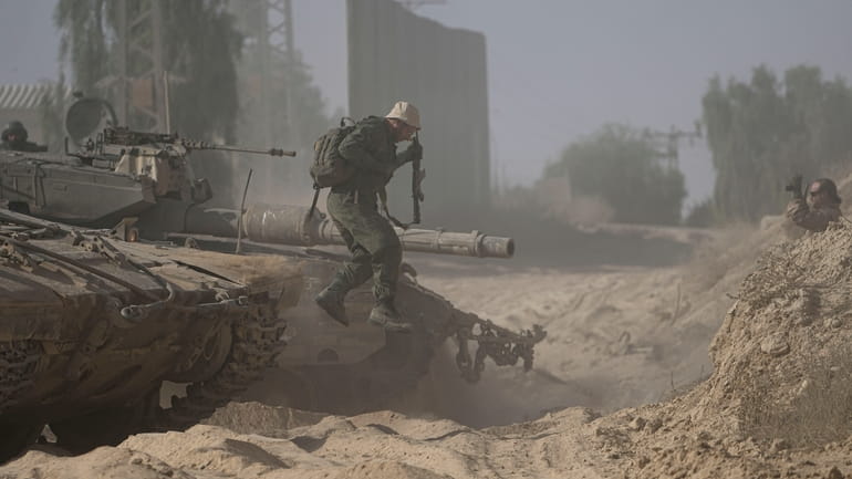 An Israeli soldier dismounts from his tank near the Israel-Gaza...