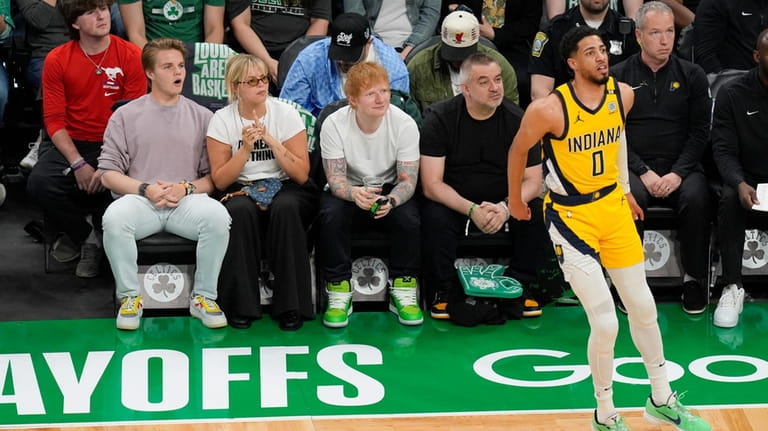 Ed Sheeran, citing at center, watches as Indiana Pacers guard...