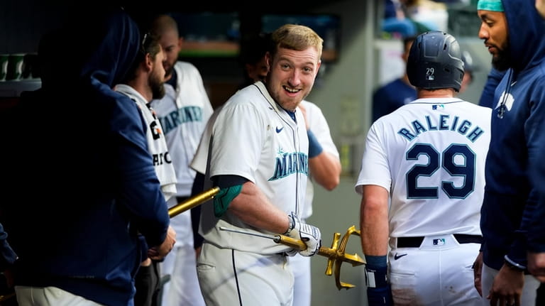 Seattle Mariners' Luke Raley, facing, reacts after breaking the trident...