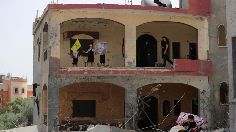 A girl waves a Hezbollah flag as her brothers hold...