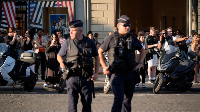 People watch police officers guarding the area on the Champs-Elysees...