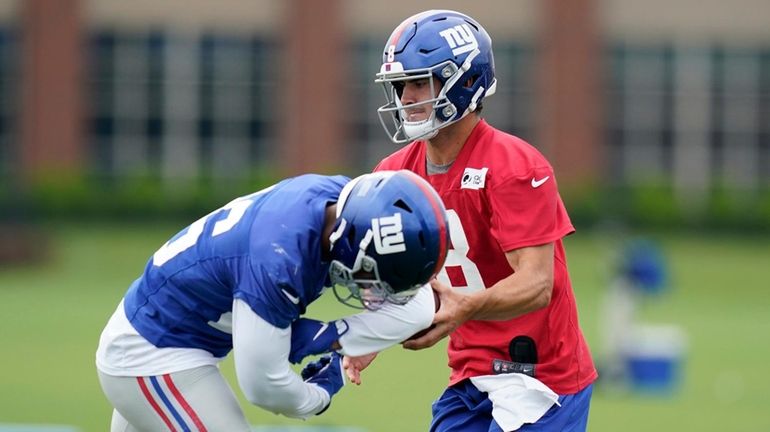 Giants quarterback Daniel Jones, right, fakes a handoff to Saquon...