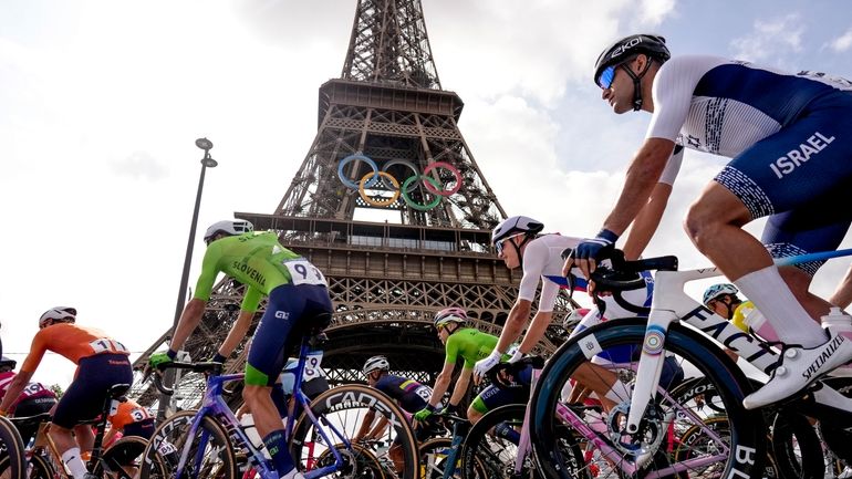 Competitors pass by the Eiffel Tower as they start the...