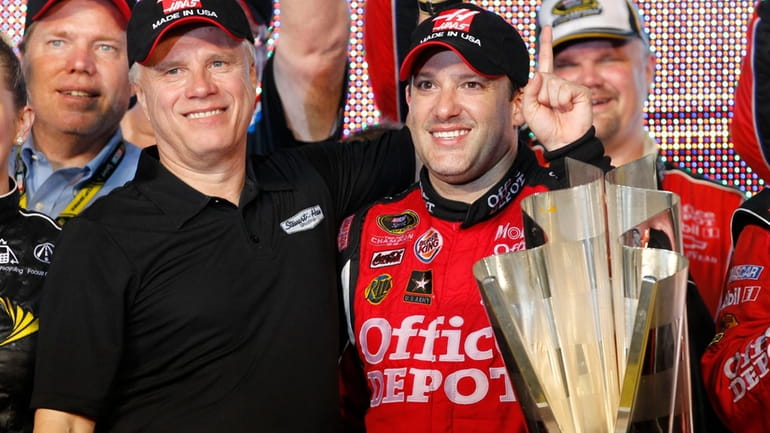Team co-owner Carl Haas and Tony Stewart, right, pose with...