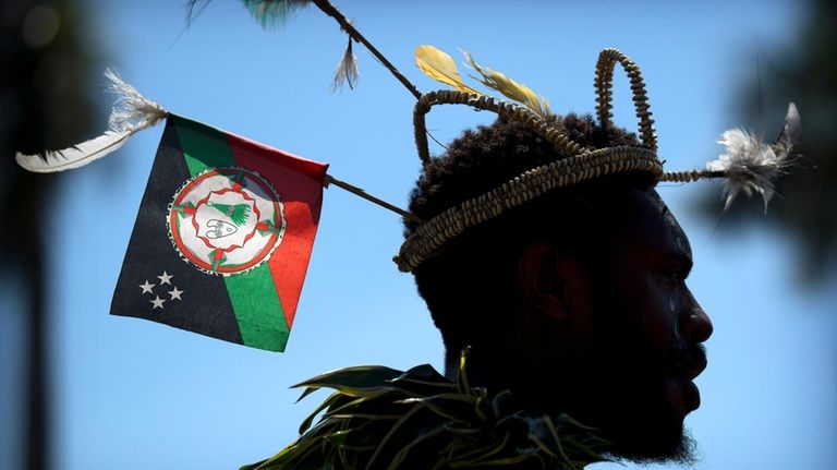 A performer in traditional dress stands before a welcome ceremony...