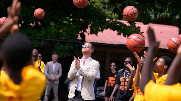Prince Harry, center, plays basketball with children during the Giant...