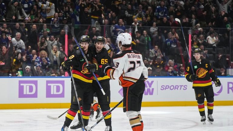 Vancouver Canucks' Elias Pettersson, back left, and Ilya Mikheyev (65)...