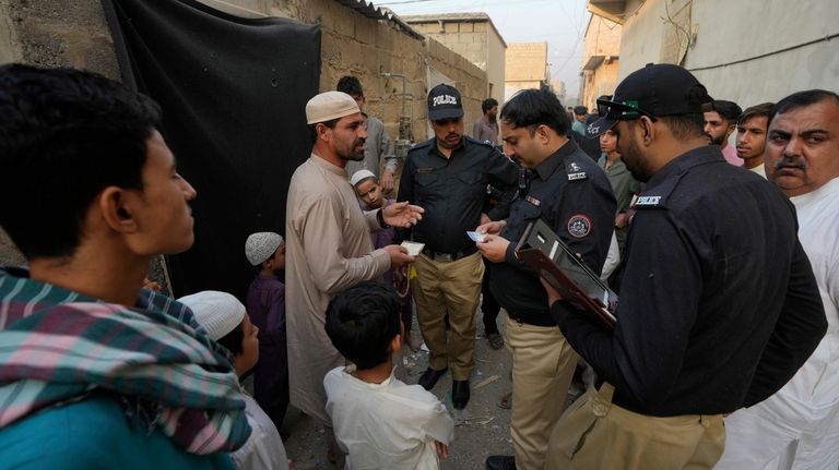 A Police officer checks documents of a resident during a...