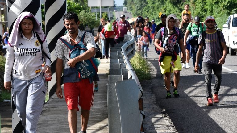 Migrants walk along the highway through Suchiate, Chiapas state in...