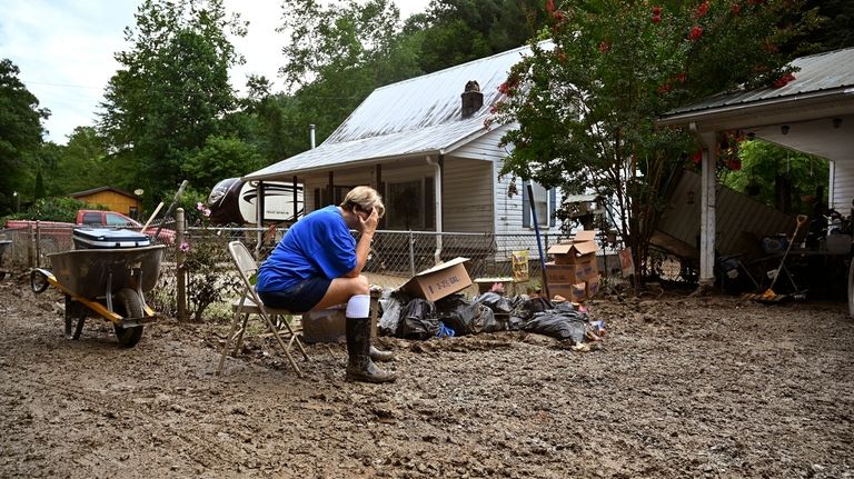 Teresa Reynolds sits as members of her community clean the...