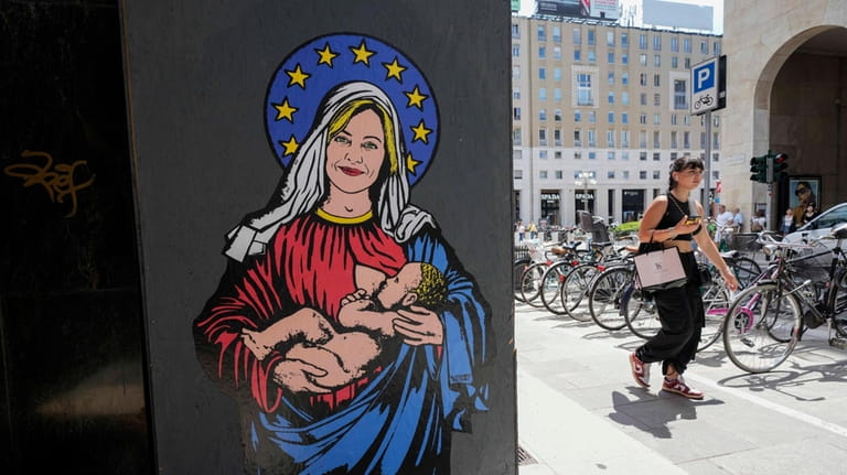 A woman passes by a mural called "Santa Giorgia' by...