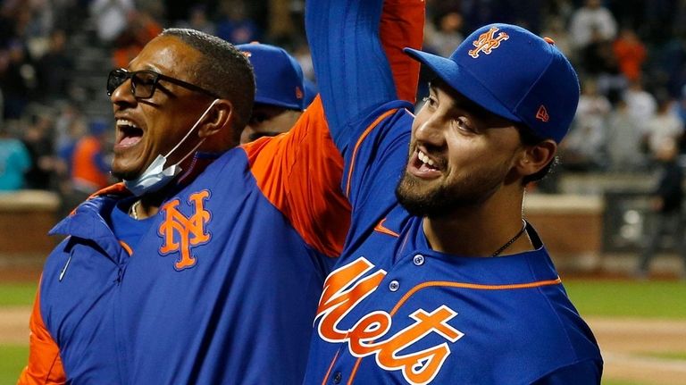 Michael Conforto of the Mets and first base coach Tony Tarasco reacts...