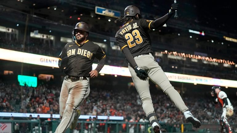 San Diego Padres' Trent Grisham, left, runs toward Fernando Tatis...