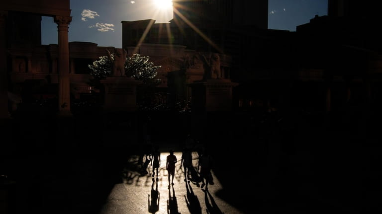 People walk in the sun along the Las Vegas Strip,...