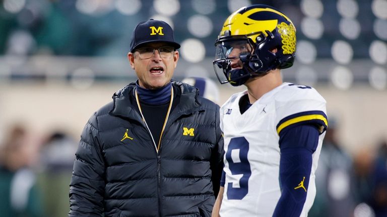 Michigan coach Jim Harbaugh, left, talks to quarterback J.J. McCarthy...