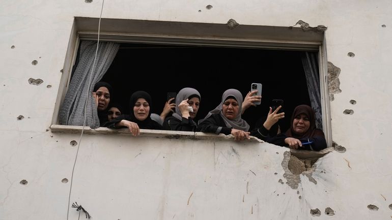 Mourners watch the funeral of Palestinian men who were killed...