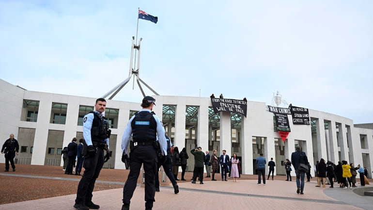 Pro-Palestinian protesters hang banners from the top of Parliament House...