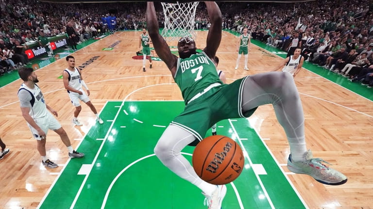 Boston Celtics guard Jaylen Brown (7) hangs on the rim...